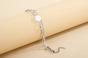 Double-layered silver snake and paperclip chain bracelet with a white shell flower charm