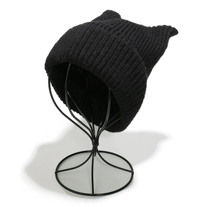 Detailed view of thick black knitted cat ear hat with texture on metal display stand