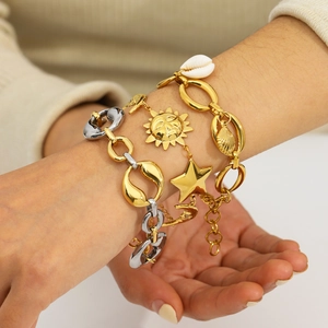 Gold and silver layered bracelet set with sun, star, and shell charms on a model wrist