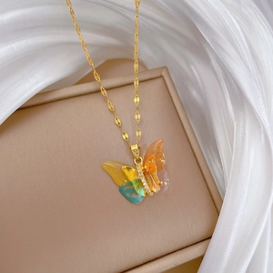 Macro view of colorful butterfly pendant with gold foil and crystals on a fine gold chain