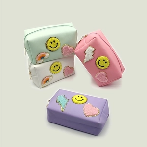 Detailed view of chenille patch embroidery on pastel PU leather makeup bags with zip closure