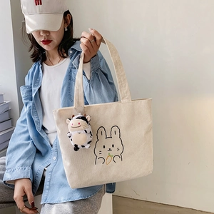 Beige corduroy tote bag with cartoon rabbit embroidery and a small cow plush charm
