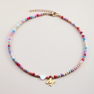 Detail of colorful beaded necklace with golden M initial pendant and white heart bead