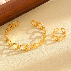 Detailed close-up of a gold heart jewelry set with cutout hollow heart bangle and ring