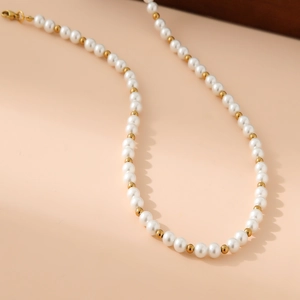 Detailed macro view of white faux pearls with gold beads and a secure lobster clasp