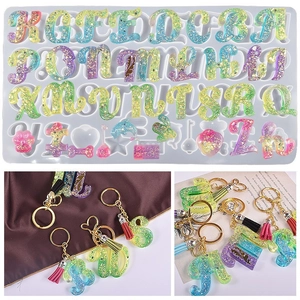Détail de moules alphabet en résine avec porte-clés arc-en-ciel et pompons colorés