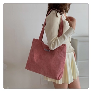 Close-up of pink corduroy tote bag with Fashion label worn by model on shoulder