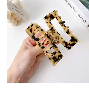 Minimalist square tortoiseshell acetate hair claw clip held by hand for styling