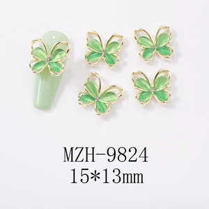 Macro view of gold bow-knot nail charms with green opal stone and tiny diamonds