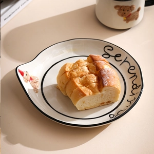 Detail of white ceramic plate with a cute 3D brown bear handle and Serendipity text