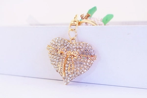 Detail of a golden heart keychain with sparkling rhinestones and a central bow accent