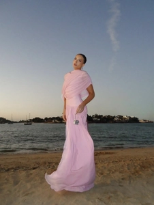 Elegant long pink chiffon dress flowing in the wind at a sunset beach setting