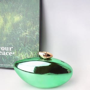 Close-up of a green shell evening clutch with metallic gloss and golden clasp hardware