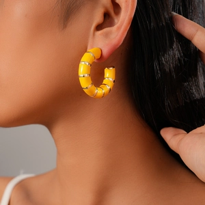 Close-up of model wearing yellow C-shaped geometric hoop earrings with gold metal rings