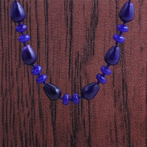 Vue détaillée du collier de perles bleu foncé en forme de larme et de disque lisse