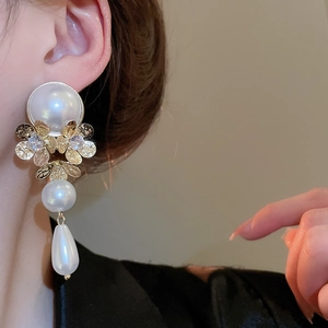 Detail of luxury flower tassel earrings with large white pearls and gold petal textures