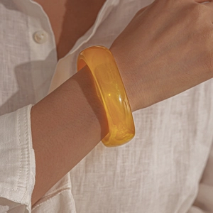 Detail of a translucent amber resin wide bangle bracelet with subtle inner textures