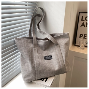 Detailed close-up of light grey tote bag showing canvas texture and fashion patch label