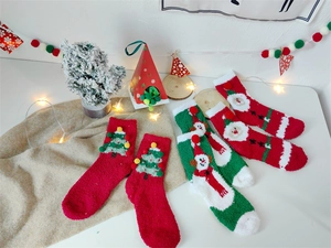 Détail de chaussettes de Noël en polaire corail avec pompons et motifs festifs