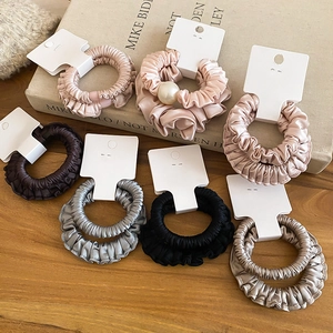 Détails de chouchous en satin plissé avec perles élégantes présentés sur une surface en bois