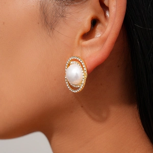 Close-up of elegant oval pearl stud earring with double halo rhinestones on gold base