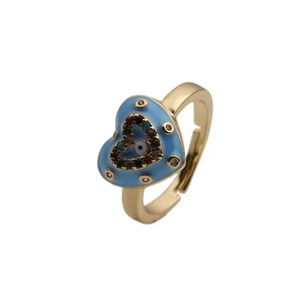 Macro detail of gold plated heart ring featuring blue enamel and zircon evil eye design