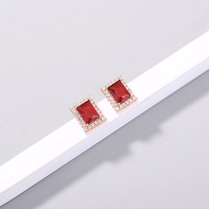 Close-up of gold clover earrings with rectangular ruby red stone and zircon pavé