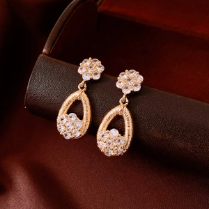 Macro view of 18K gold plated teardrop earrings with CZ flower studs and brushed texture