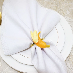 Macro detail of a banana-shaped napkin ring on white fabric and ceramic plate