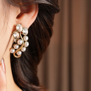Close-up of vintage gold floral earrings with crystal pavé and white round pearls