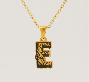 Detailed view of the 18k gold letter E pendant featuring unique black texture accents