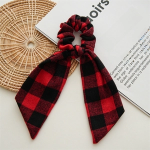 Detail of red and black buffalo plaid scrunchie with long ribbon on a vintage book