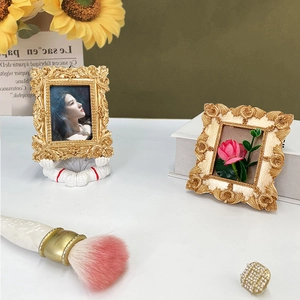 Close-up of European retro photo frames in gold and cream resin on a vintage desk