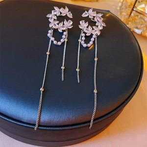 Détail de boucles d'oreilles feuille zircon argent avec perles et longs pompons sur coffret