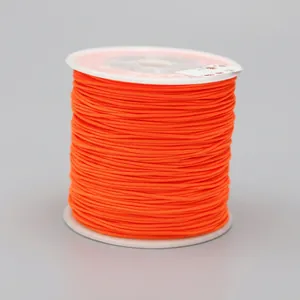 Macro detail of 0.8mm bright orange braided nylon cord on white spool for DIY jewelry crafts