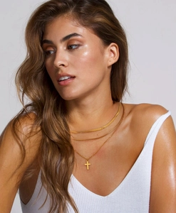 Detailed view of triple-layered gold stainless steel necklace with cross pendant on model