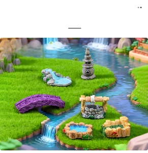 Miniature garden resin bridge and stone well ornaments on synthetic lawn detail