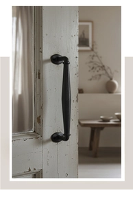 Detail of vintage black cast iron door handle with hammered texture on a rustic wooden door