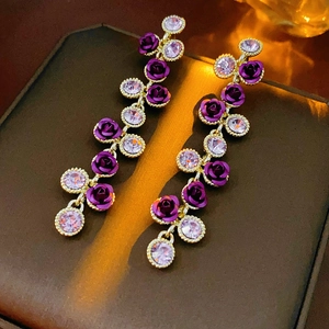 Détails de boucles d'oreilles dorées à pampilles avec roses violettes et cristaux