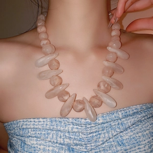 Detailed view of oversized beaded necklace with translucent milky resin drop pendants