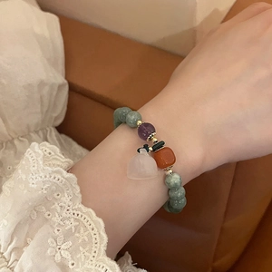 Detail view of jade bead bracelet with chalcedony beads and white bell charm on wrist
