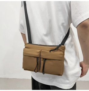 Brown nylon messenger bag shown on model featuring two drawstring utility front pockets