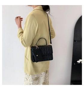 Quilted black crossbody bag with detachable coin purse shown on a model in a yellow blazer