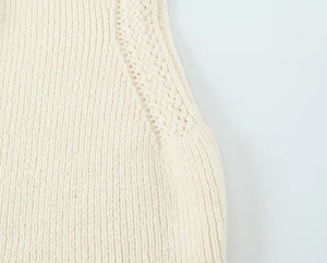 Gros plan sur la texture du tricot crème et les détails de couture sur l'épaule