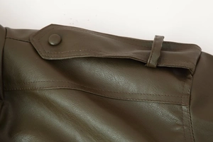 Detailed view of dark brown PU leather jacket shoulder strap with stitching and metal button