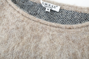 Close-up of crew neck detailing and woven brand label on camel knit sweater