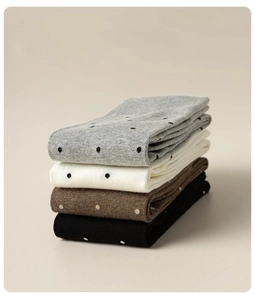 Detail of four pairs of knitted cotton socks with polka dots in grey, white, brown, and black