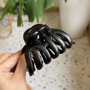 Detailed close-up showing the matte black texture and multi-tooth design of the pumpkin hair claw