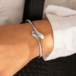 Dettaglio del bracciale rigido aperto argento con intarsio in conchiglia bianca sul polso