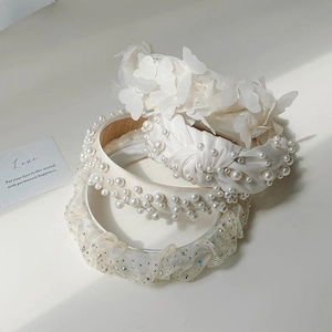 Close-up of four creamy white headbands featuring lace, pearls, and satin textures